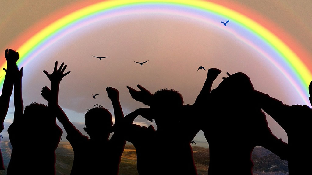 Siluetas de niños de espaldas mirando hacia el arcoiris